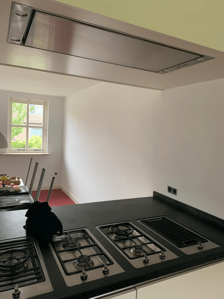 Strak gespoten plafond met inbouw afzuigkap boven een kookeiland