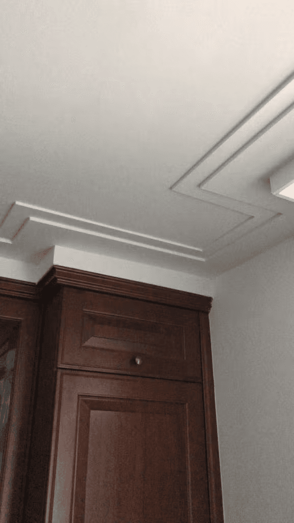 Plafond met sierlijst en kooflijst detail naast een houten kast